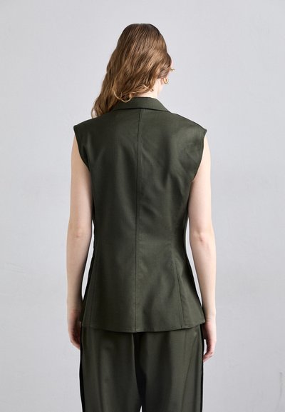 Saldžiosios žalios spalvos be rankovių švarkas su struktūruotomis pečių linijomis, pritaikytu siluetu ir nugaros siūlėmis. Medžiaga atrodo lygi su matinio paviršiaus finis.