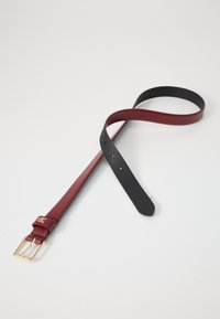 Ceinture avec une sangle en cuir bordeaux, présentant un dessous noir, une boucle en métal doré et plusieurs trous d'ajustement le long de la longueur.