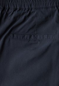 Mörkblå tygshorts med elastisk midja, utrustade med en enda fackficka på baksidan, slät textur och minimal sömdekoration.