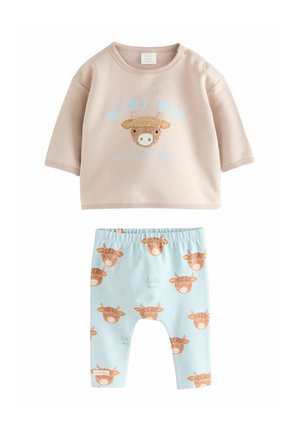 Haut à manches courtes rose clair avec un graphique de vache et un pantalon bleu à motifs de vaches. Les deux sont en tissu doux, conçus pour les nourrissons.