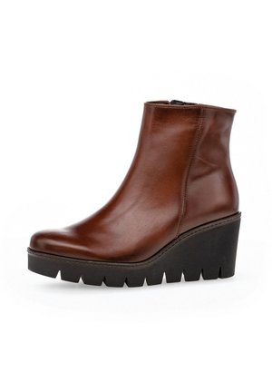 Bottine en cuir marron au design épuré, avec une semelle compensée haute et une plateforme texturée noire. Fermeture à glissière sur le côté pour un enfilage facile.