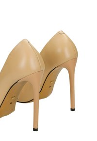 Béžové lodičky s úzkou špičkou, vyrobené z hladké kůže, s tenkým stiletto podpatkem a minimálními detaily šití.