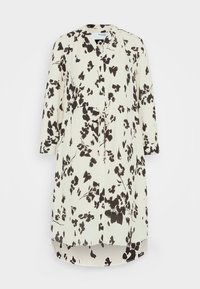 Valkokukkakuosiset mekko, jossa on mustia yksityiskohtia, V-pääntie, pitkät hihat ja kiristettävä vyötärö. Takana on hieman pidempi.