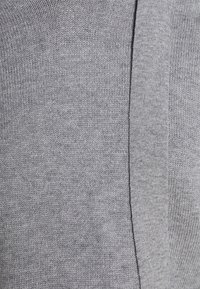 Grå stickad tyg med en strukturerad mönstring, ribb och en slät yta. Materialet är mjukt och lätt.