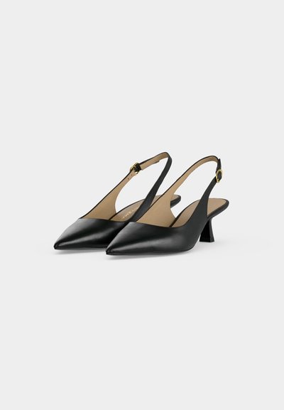 Paire d'escarpins slingback noirs à bout pointu, à talon bloc de hauteur moyenne et brides de cheville à boucle dorée, présentés sur un fond clair et uni.