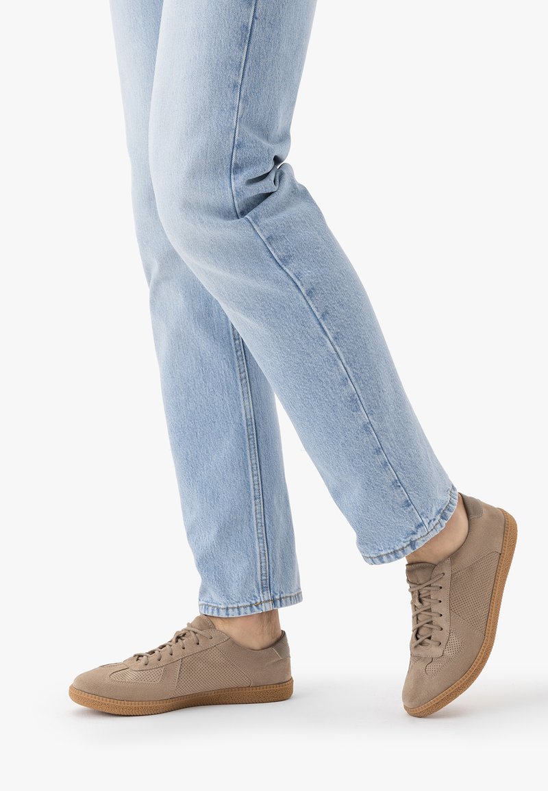 Heledatesinised teksad koos pruunide seemisnahast paeltega tossudega valgel taustal, kuvades lõdvestunud vabaaja stiili.