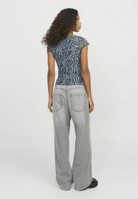 Top aderente blu con stampa zebra a maniche corte abbinato a jeans grigi larghi. Il top ha un aspetto testurizzato e ruches sul retro.
