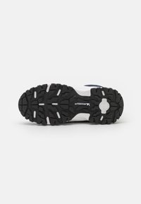 Schwarze Gummisohle mit multidirektionalen Stollen, weiße Zwischensohle und blaue Akzente. Verfügt über ein strukturiertes Profil für Grip und Stabilität.