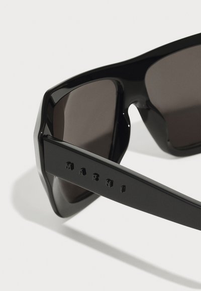 Black sunglasses with an angular frame, dark tinted lenses, and raised "Marni" branding on the side of the arm. Smooth, glossy texture.