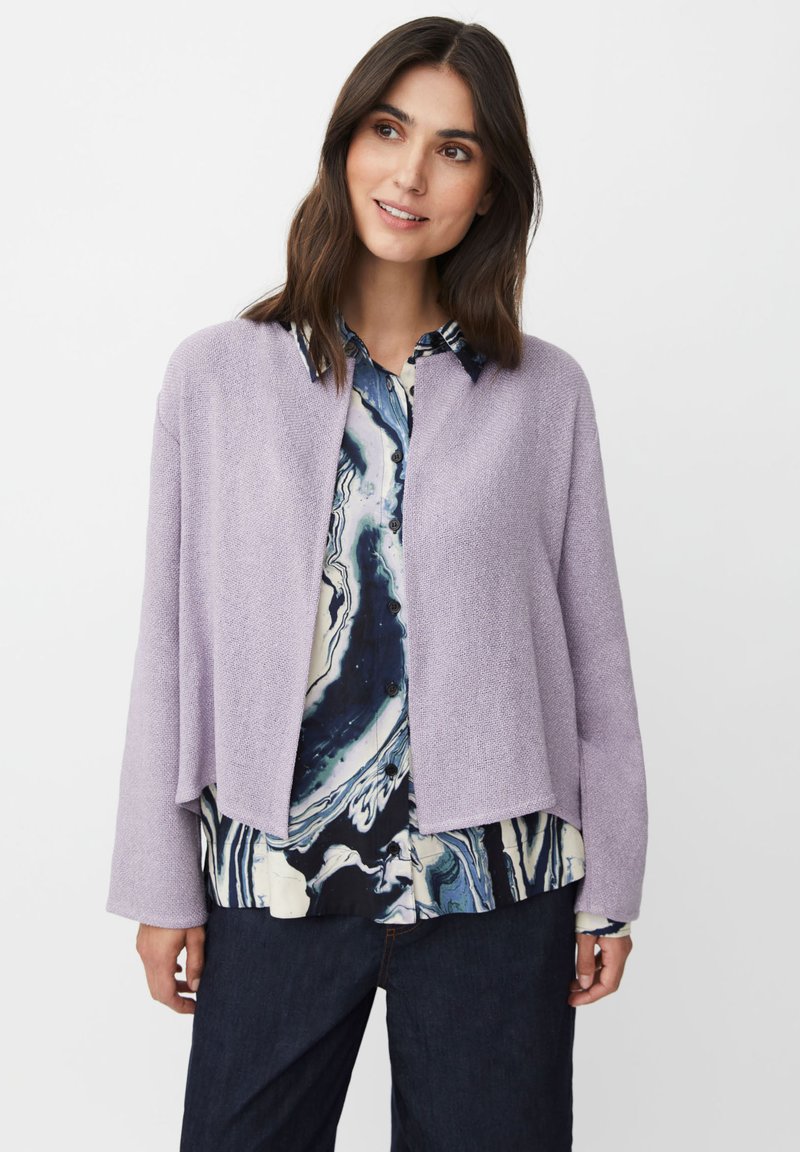 Ljust lila, strukturerad cardigan med öppen framsida och långa ärmar, lagd över en mönstrad blå och vit skjorta, i kombination med mörka jeans.