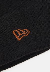 Gorro de lana negro con textura acanalada, que presenta un destacado logotipo bordado en naranja en un lado. Diseño simple y funcional.