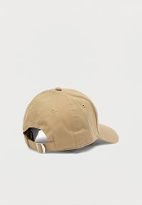 Khakivärinen puuvillainen lippis, jossa kaareva lippa ja takana säädettävä hihna metallisoljella. Sileä pinta, yksinkertainen muotoilu.