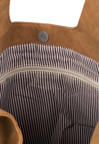 Hnědá koženková taška s látkovým vnitřkem pruhovaným v hnědých a bílých tónech, vybavená vnějším patentním zapínáním a kapsou na zip.