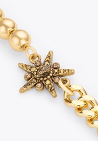 Bracciale con perline dorate caratterizzato da un charm a forma di stella marina con una superficie texturizzata e strass incastonati, che completa il design a catena.