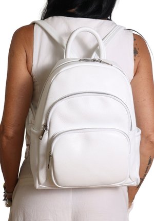 Zaino in pelle bianca con forma arrotondata, tasca frontale con zip e doppie cinghie. Finitura testurizzata e dettagli in hardware argentato lucido.