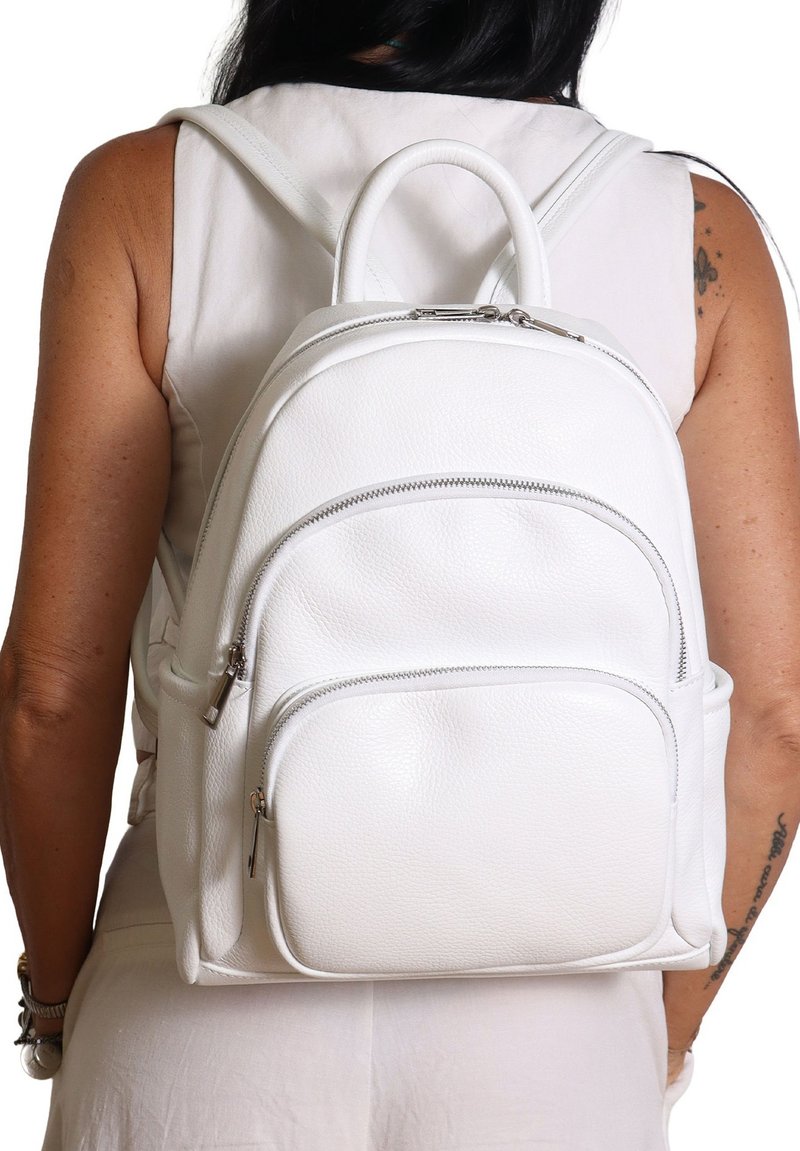 Zaino in pelle bianca con forma arrotondata, tasca frontale con zip e doppie cinghie. Finitura testurizzata e dettagli in hardware argentato lucido.