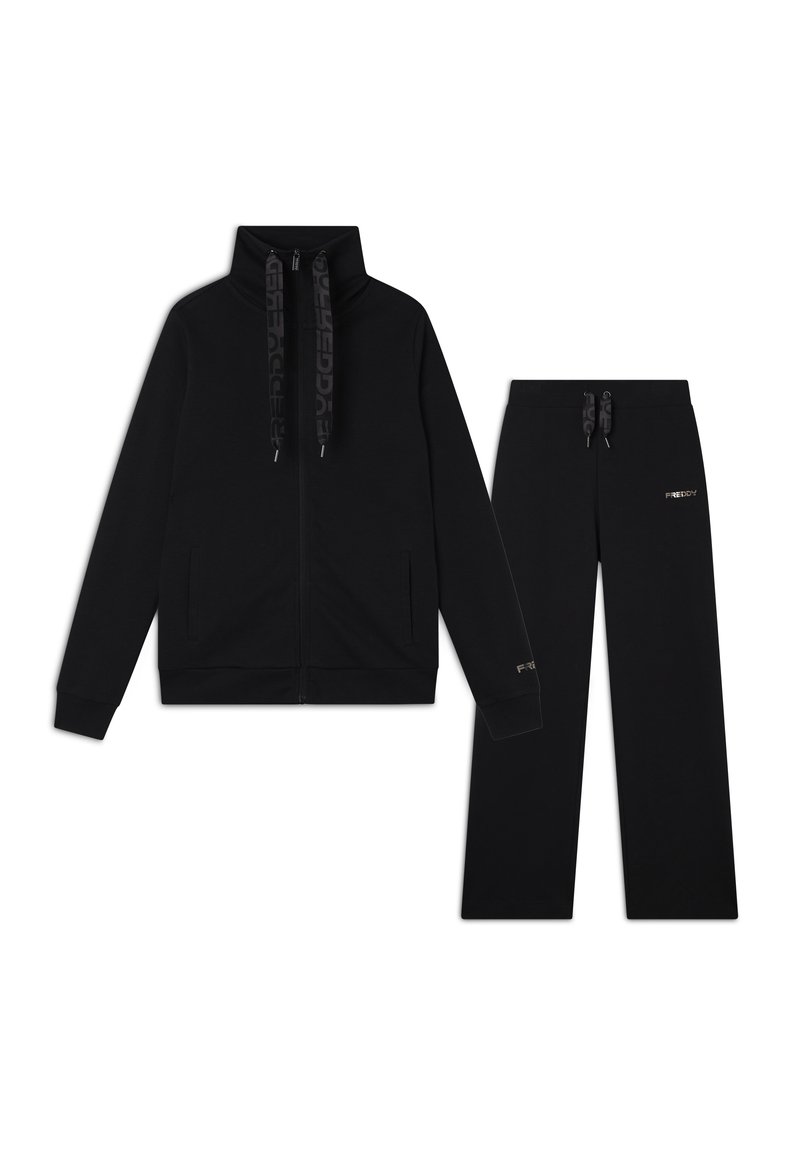 Felpa nera con zip e colletto alto, caratterizzata da cordini con motivo e tasche laterali. Pantaloni sportivi neri abbinati con vita elastica e logo.