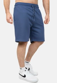 Pantaloni corti in cotone blu con elastico in vita, cordoncino e tasche laterali. Design semplice con vestibilità regolare, adatti per un abbigliamento informale.