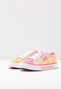 Baskets en toile tie-dye rose et jaune avec des lacets blancs et une semelle en caoutchouc, présentant un accent rayé sur le côté.