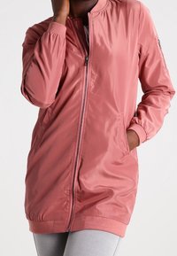 Light pink, zip-up bomber jacket with a round collar, elastic cuffs, and side pockets. Smooth, shiny fabric with a relaxed fit.