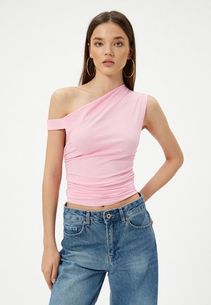 Top rosa, elástico, de un solo hombro con detalles fruncidos. Combinado con unos vaqueros de mezclilla azul claro, de cintura alta. Diseño simple y ajustado.
