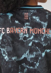 Mustekko mustasta ja turkoosista, jossa on "FC BAYERN MÜNCHEN" ruusukultaisilla kirjaimilla. Yllä on pieni teksti "MIA SAN MIA", ja kauluksessa on ribat.