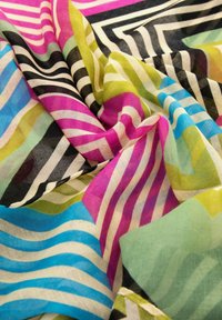 Tissu multicolore avec des motifs fluides en rose, vert, bleu et noir. Présente des rayures et des lignes ondulées sur une texture légère et translucide.