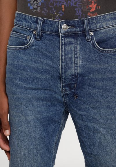 Indigo Denim-Jeans mit klassischer Passform, fünf Taschen und einem Reißverschluss mit einem silbernen Knopf. Leichte Abnutzung im Stofftextur.