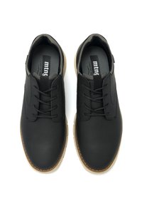 Zapatos negros con cordones, hechos de material sintético liso, con una suela de goma marrón claro en contraste y un sutil logo en el forro interior.