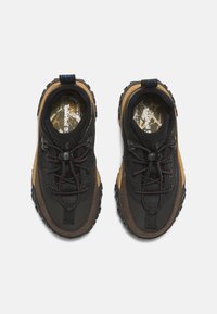 Černé a hnědé turistické boty s texturovanou látkou, gumovými podešvemi a tmavými tkaničkami. Mají modrou poutací tabulku a vzorované stélky.