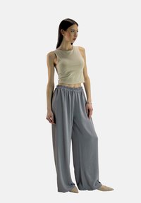 Lichtgrijze wijde broek met een elastische tailleband, gecombineerd met een beige mouwloze crop top. Gladde stof met een ontspannen pasvorm.