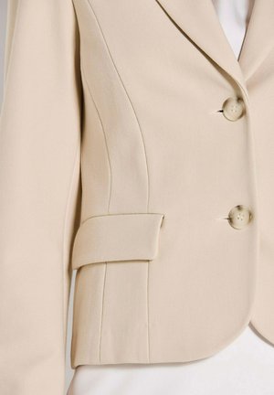 Beiger Blazer mit strukturiertem Stoff, Reverskragen mit Kerbe, zwei Vorderknöpfen und einer Seitentasche mit Klappdetail.