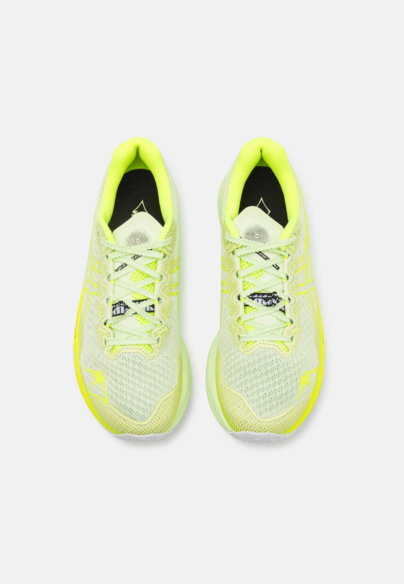 Zapatillas deportivas de color amarillo claro que cuentan con una parte superior de malla texturizada, detalles en amarillo y una plantilla negra con un logotipo. Cierre de cordones con bordes redondeados.