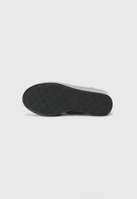 Svart sneaker såle med et teksturert houndstooth mønster, med en jevn kant og avrundet form. Ingen synlige logoer eller metalldetaljer.