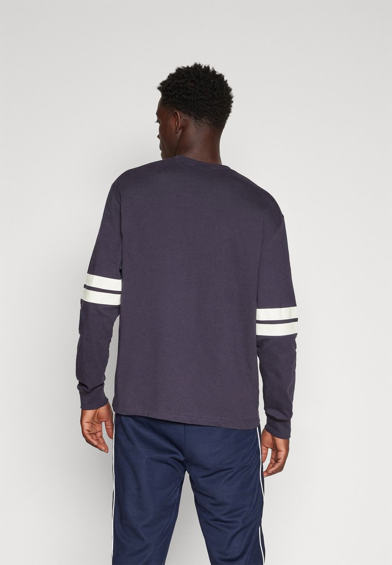 Navy longsleeve t-shirt met witte strepen op de mouwen, ronde halslijn en een comfortabele pasvorm, gemaakt van zachte katoenen stof.