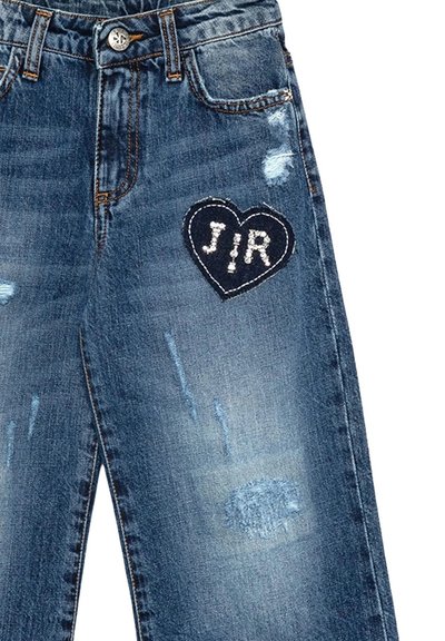 Jeans in denim blu con dettagli strappati e una patch a forma di cuore con le lettere "J" e "R" decorate in bianco. Design standard a cinque tasche.
