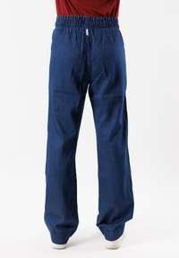 Pantaloni in denim blu con vita elastica, design a gamba dritta e superficie uniforme. Il tessuto sembra morbido e leggermente strutturato.