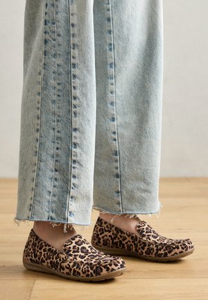 Slip-on sko med leopardprint, rund tå og tan sål, parret med lyseblå jeans med forskydning i kanten, hvilket giver et afslappet look.