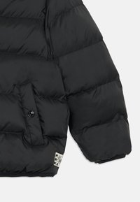 Černá péřová bunda s rukávem, který má kapsu na knoflík, prošívanou texturu a logový štítek s kostkovaným vzorem na spodním okraji.