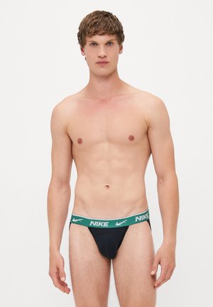 Schwarzer Nike-Tanga mit einem grün-weißen Markenbund, aus einem glatten, elastischen Stoff und einem figurbetonten Design.