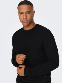 Black knitted sweater with a geometric textured pattern, ribbed cuffs, and crew neckline. The fabric appears thick and warm.