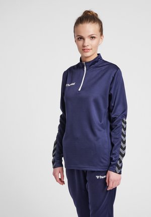 Marineblauw sportief lang goed met kwart rits, voorzien van textuurstof en zwarte chevronpatronen op de mouwen. Logo op de borst.