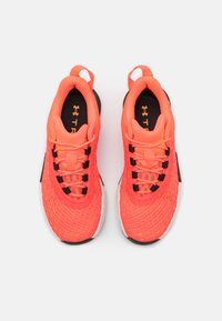 Scarpe da ginnastica arancioni vivaci con una tomaia in rete testurizzata, lacci neri e una suola intermedia bianca, dotate di una linguetta sul tallone.