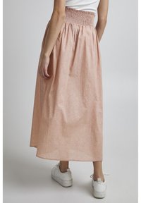 Gonna lunga rosa con vita arricciata e motivo intricato. Il tessuto sembra leggero, con una silhouette fluida e un design lungo fino alla caviglia.