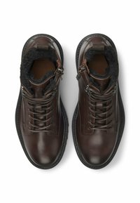 Bruine leren enkelboots met een gestructureerde zwarte bontvoering, verstelbare veters en ritsen aan de zijkanten voor gemakkelijk aan- en uittrekken.