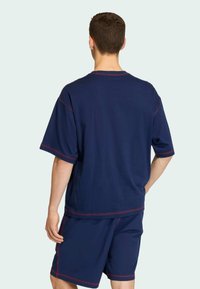 Námořnická modrá souprava trička a šortek s červenými švy. Uvolněný střih, krátké rukávy a měkká textilie.