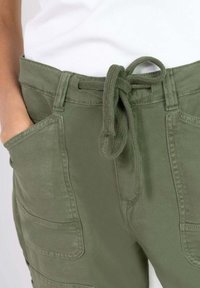 Pantalones cargo de color oliva con cintura ajustable, bolsillos laterales y un corte relajado, fabricados en una resistente mezcla de algodón.