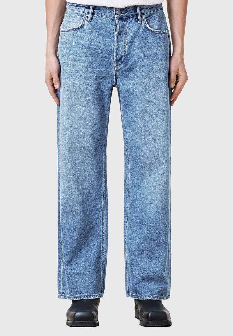 Jeans din denim de un albastru deschis, cu picioare largi, cinci buzunare și o cusătură în contrast. Materialul pare ușor uzat, având o textură netedă.
