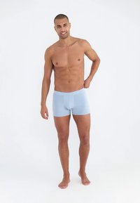 Svetlo modre bokser hlačke iz mehkega, raztegljivega materiala; oprijet kroj z pasom srednje višine; minimalno vidnih šivov in podrobnosti.