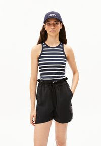 Top senza maniche a righe blu navy e bianche abbinato a pantaloni corti neri a vita alta. I pantaloni corti hanno un cordino e tasche laterali.